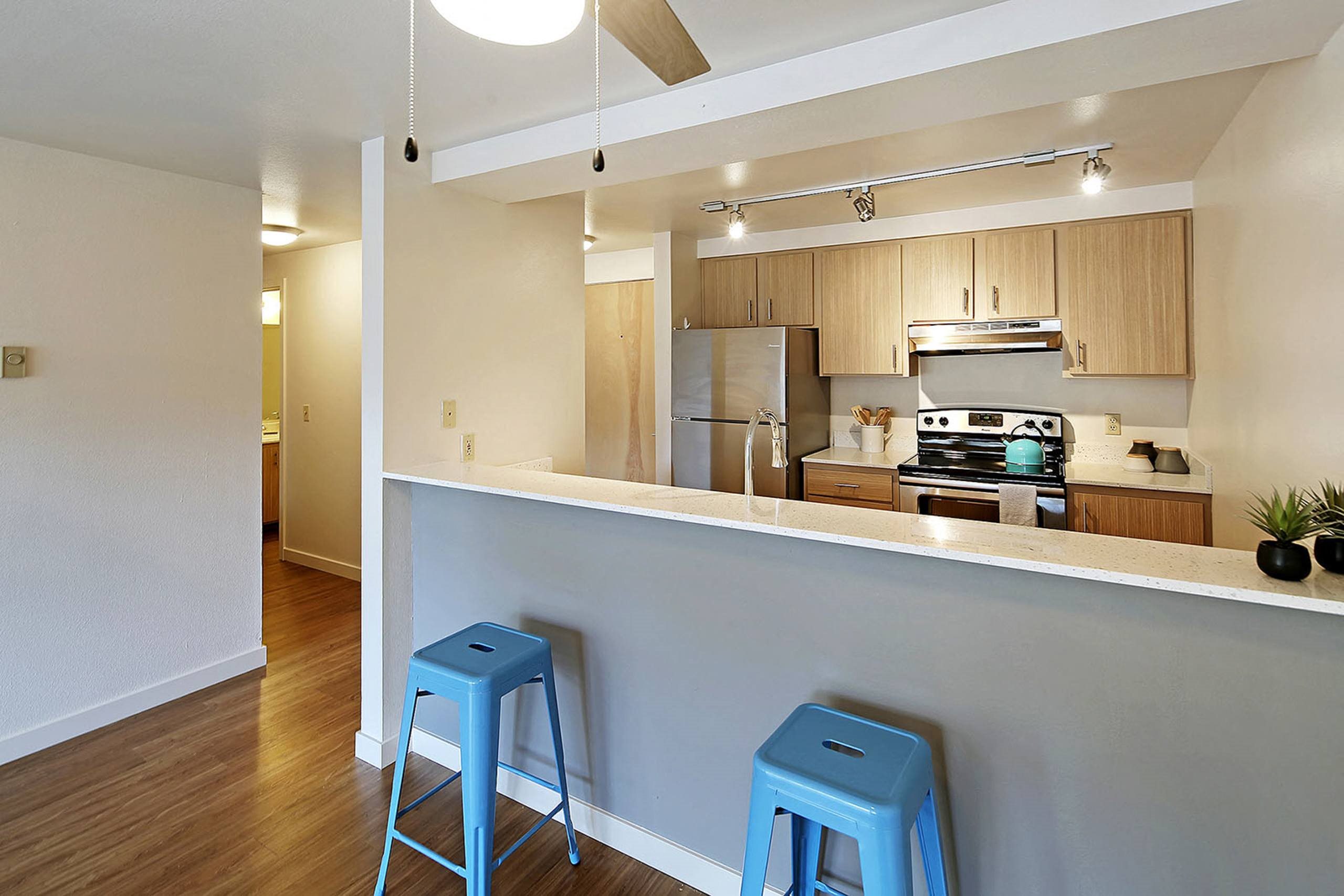 a kitchen with two blue stools in front of a counter  at Townside Flats, Redmond, 98052